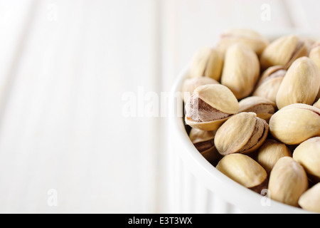 Haufen von Pistazien im Cup und leeren Bereich auf der linken Seite für Text. Selektiven Fokus auf Pistazie auf der linken Seite Stockfoto