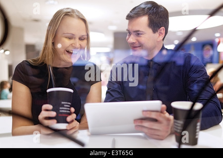 Frau lacht wie Mann Tablet zeigt Stockfoto