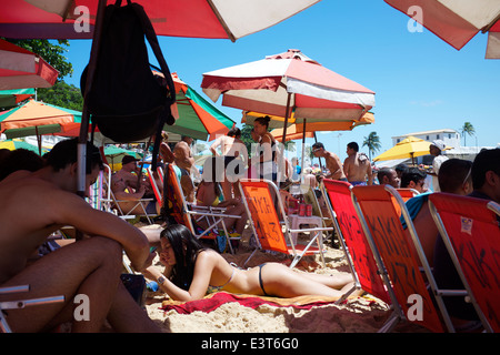 SALVADOR, Brasilien - 13. Oktober 2013: Brasilianische Männer und Frauen entspannen Sie sich auf Liegestühlen und den Sand am Strand von Porto da Barra. Stockfoto