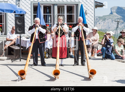 Schweizer Musiker in traditioneller Tracht spielt das Alphorn in männlichen, Wengen, Berner Oberland, Schweiz Stockfoto