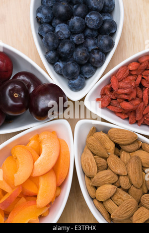 Eine Auswahl an gesunden Snacks wie Aprikosen, Mandeln, Kirschen, Heidelbeeren und Goji-Beeren. Stockfoto