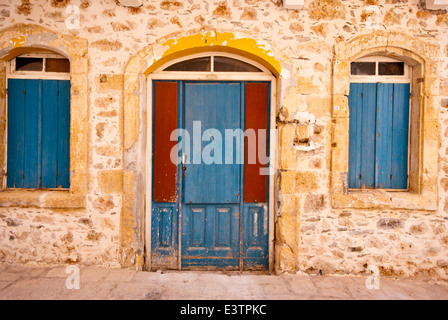 Alte rustikale blau hölzerne Eingangstür und blau hölzernen Fensterläden auf einem kretischen traditionellen Haus Stockfoto