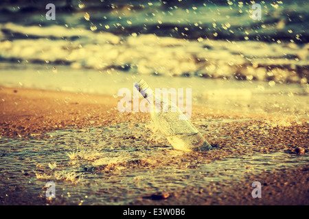 Flasche mit Wasser tropft auf Strand, Retro-Instagram-Vintage-Effekt. Stockfoto