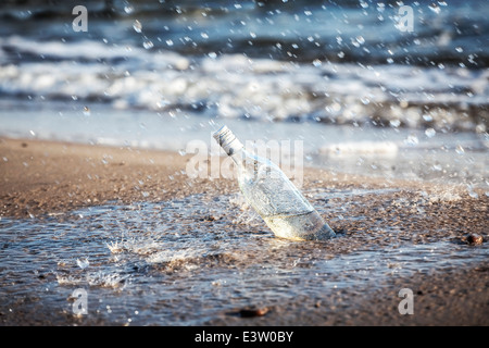 Flasche mit Wasser Tropfen am Strand. Stockfoto