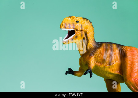 Spielzeug-T-Rex auf grün / blauen Hintergrund isoliert Stockfoto