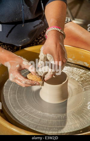 Ein Tontopf wird gesponnen auf einer Töpferscheibe in einer High-School-Keramik-Klasse in San Clemente, CA. Hinweis Schwamm, den feuchten Ton zu gestalten. Stockfoto