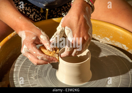 Ein Tontopf wird gesponnen auf einer Töpferscheibe in einer High-School-Keramik-Klasse in San Clemente, CA. Hinweis Schwamm, den feuchten Ton zu gestalten. Stockfoto