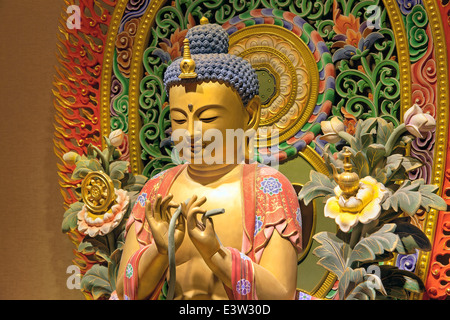Holz geschnitzt bunte sitzende Buddha-Statue mit aufwendigen farbigen Hintergrund Closeup Stockfoto