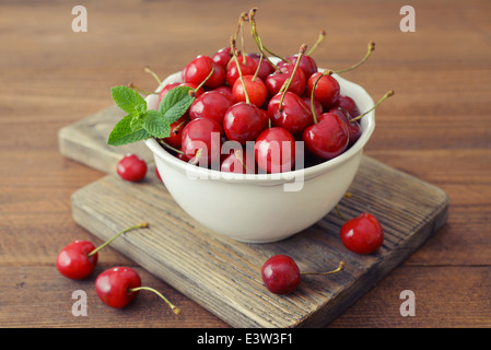 Frische süße Kirschen in Schüssel auf hölzernen Hintergrund Stockfoto