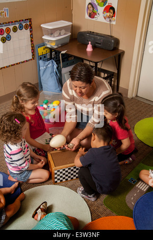 Halten Sie ein großen künstlichen Ei, zeigt Hispanic Lehrer Vogel Nester für Kleinkinder in einem "Learning Link" Klassenzimmer in Tustin, Kalifornien, Durchführung eines Workshops in interaktives Verhalten. Mit speziell entwickelten Aktivitäten, lehrt die Klasse Eltern ihren Kindern sinnvolle Spiel betreiben. Beachten Sie die künstlichen Eiern im Feld. Stockfoto