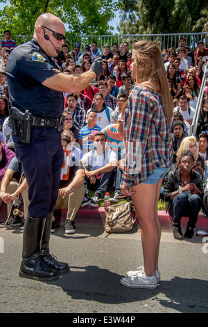 Eine freiwillige High-School-Mädchen spielt die Rolle eines Treibers von einem Polizisten in eine Dramatisierung der Gefahr der Trunkenheit am Steuer für die Erziehung der Mitschüler in Anaheim, CA. Hinweis multirassische studentische Publikum im Hintergrund verhört. Stockfoto