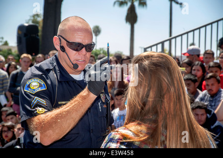 Eine freiwillige High-School-Mädchen spielt die Rolle eines Treibers verhört von einem Polizisten in eine Dramatisierung der Gefahr von Trunkenheit am Steuer in Anaheim, Kalifornien, als er einen Stift vor ihren Augen zu testen Sie ihr Niveau des Rausches bewegt sich. Beachten Sie die multirassische studentische Publikum im Hintergrund. Stockfoto