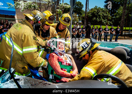 Anaheim, CA, entfernen Feuerwehrmänner Freiwilligen "Opfer" von einem zertrümmerten Auto eine Dramatisierung eines Verkehrsunfalls, Schülerinnen und Schüler zeigen die Gefahren von Alkohol am Steuer beteiligt. Beachten Sie Jugendliche in "Grim Reaper" Kostüme im Hintergrund. Stockfoto