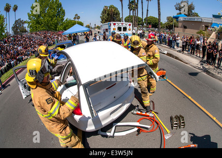 Anaheim, CA, entfernen Feuerwehr das Dach ein Autowrack angeblich eine Dramatisierung eines Verkehrsunfalls, Schülerinnen und Schüler zeigen die Gefahren von Alkohol am Steuer beteiligt. Beachten Sie Publikum im linken Hintergrund und Krankenwagen. Stockfoto