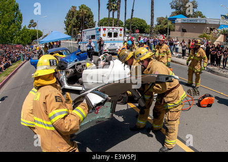 Anaheim, CA, entfernen Feuerwehr das Dach ein Autowrack angeblich eine Dramatisierung eines Verkehrsunfalls, Schülerinnen und Schüler zeigen die Gefahren von Alkohol am Steuer beteiligt. Beachten Sie Publikum im linken Hintergrund und Krankenwagen. Stockfoto