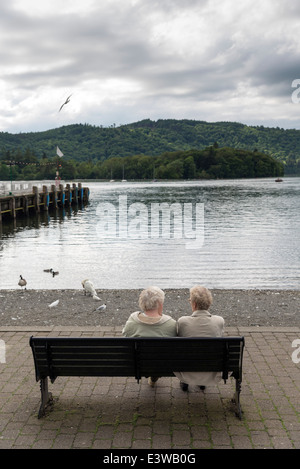 Bowness auf Windermere.Two alte Damen unkenntlich zu sprechen, sitzen auf einer Bank mit Blick auf Lake Windermere, Großbritannien Stockfoto