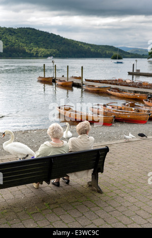 Bowness auf Windermere.Two alte Damen unkenntlich zu sprechen, sitzen auf einer Bank mit Blick auf Lake Windermere, Großbritannien Stockfoto