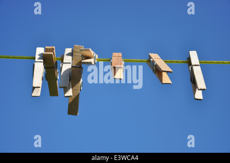 An einem sonnigen Tag hängen Holzkleider an einer Wäscheleine Stockfoto