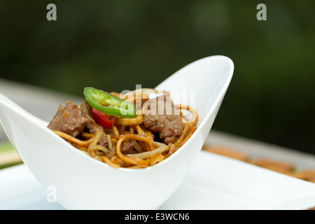 Beef Chow Mein in einer gebogenen weißen Schüssel Stockfoto