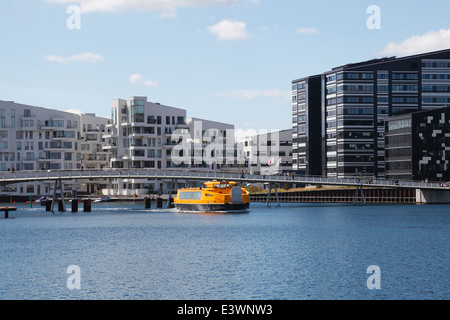 Eine gelbe Hafen Bus Unterquerung der kombinierten Rad- und Gehweg Stahl-Brücke, Bryggebroen über den Hafen von Kopenhagen, Dänemark. Stockfoto