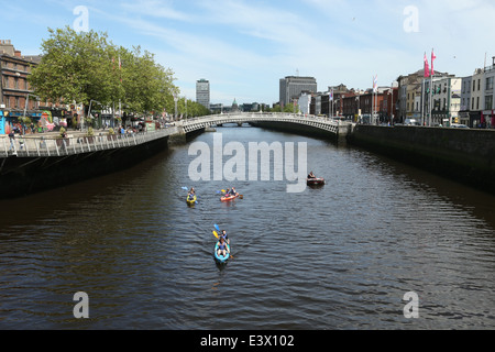 Menschen auf Kajaks Reisen entlang den Fluss Liffey im Stadtzentrum von Dublin mit der Ha'Penny-Brücke im Hintergrund Stockfoto