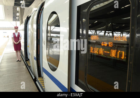 (140701)--Peking, 1. Juli 2014 (Xinhua)--eine Begleitperson steht neben einem Hochgeschwindigkeitszug für Xiamen, Provinz Fujian Südosten Chinas an der Beijing South Railway Station in Peking, Hauptstadt von China, 1. Juli 2014 verlassen. Die neue Hochgeschwindigkeits-Eisenbahnstrecke zwischen Peking und Xiamen startete seinen Betrieb am Dienstag, schneiden die Fahrzeit zwischen den beiden Städten auf weniger als 13 Stunden. (Xinhua/Li er) (Ry) Stockfoto