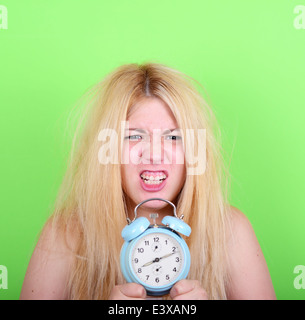 Porträt der verschlafene junge Frau im Chaos hält Uhr vor grünem Hintergrund - laufen spät Konzept Stockfoto