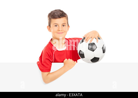 Kind hält einen Fußball hinter eine Blindplatte Stockfoto