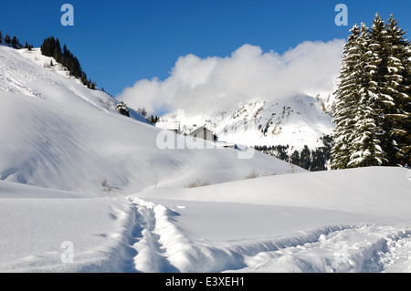 Pfad im Schnee führt durch die Berge und ein kleines Dorf Stockfoto