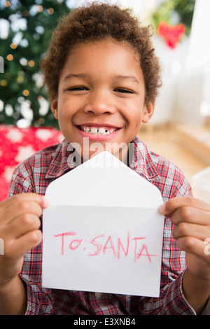 Schwarzer Junge hält Brief an den Weihnachtsmann Stockfoto