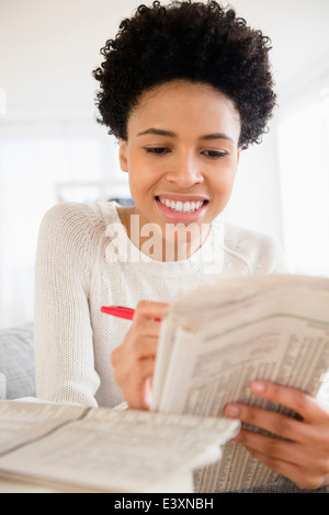 Schwarze Frau sucht Job in Zeitung Stockfoto