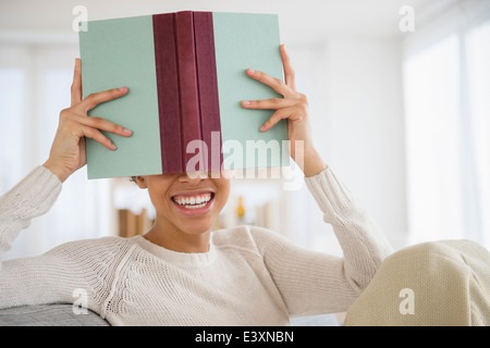 Schwarze Frau versteckt sich hinter Buch Stockfoto