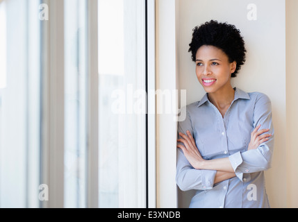 Schwarzen Geschäftsfrau lächelnd durch Fenster Stockfoto