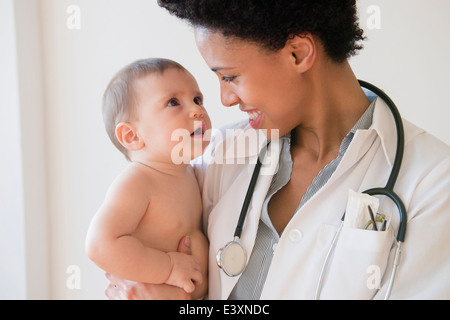 Lächelnd hält Baby Arzt Stockfoto