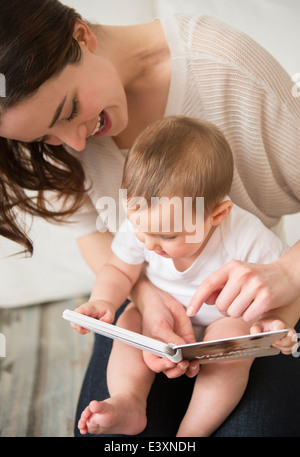 Mutter und Baby lesen im Wohnzimmer Stockfoto
