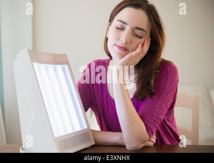 Frau sitzt durch Lichttherapie box Stockfoto