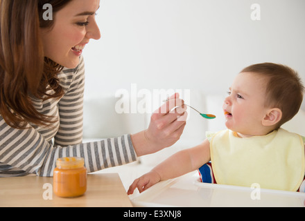 Mutter Fütterung Baby im Hochstuhl Stockfoto