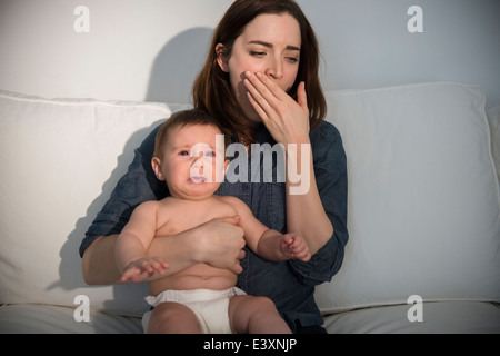 Erschöpfte Mutter Holding schreiendes baby Stockfoto