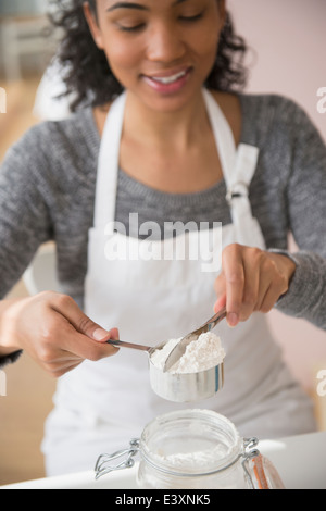 Gemischte Rassen Frau Messung Mehl in Küche Stockfoto