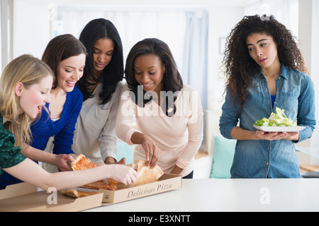 Frau mit Salat gerade Freunden Pizza essen Stockfoto