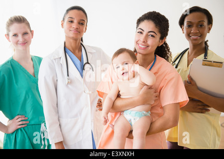 Krankenschwestern und Arzt lächelnd mit baby Stockfoto
