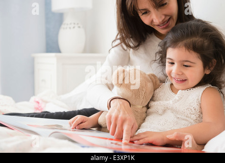 Hispanische Mutter und Tochter im Bett lesen Stockfoto