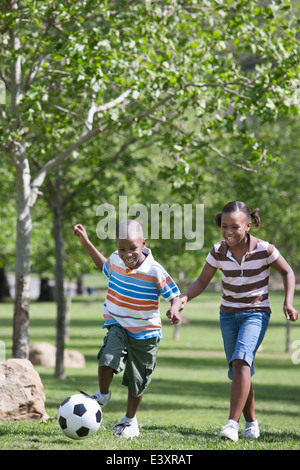 African American Kinder spielen Fußball im park Stockfoto