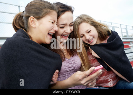 Mädchen im Teenageralter mit Handy in Decke Stockfoto