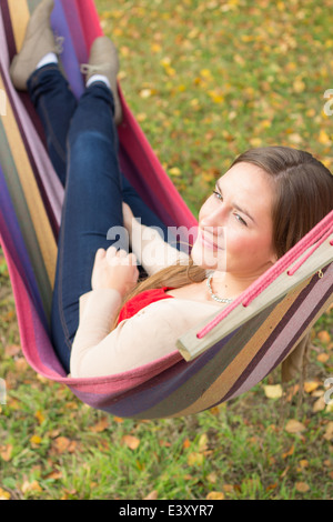 Schöne junge Frau, die in bunten Hängematte träumen Stockfoto