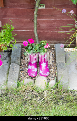 Des Kindes rosa Wellington Stiefel mit weißen Sternen als Blumentöpfe verwendet Stockfoto