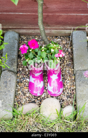 Des Kindes rosa Wellington Stiefel mit weißen Sternen als Blumentöpfe verwendet Stockfoto