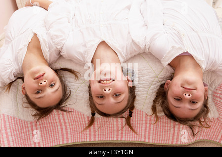 Gemischte Rassen Mädchen kopfüber aus dem Bett Stockfoto