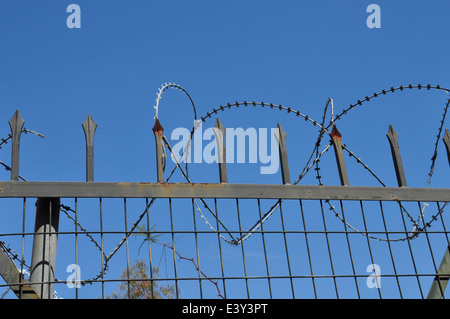 Rasiermesser-Stacheldraht und Maschendrahtzaun mit rostigen Palisade scharfe Stacheln. Immobilien Sicherheit abstrakten Hintergrund. Stockfoto