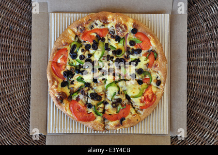 Vegetarische Pizza mit Tomaten, Oliven, Paprika, Champignons und Zwiebeln in Karton verpackt. Hintergrund der italienischen Speisen zum mitnehmen. Stockfoto